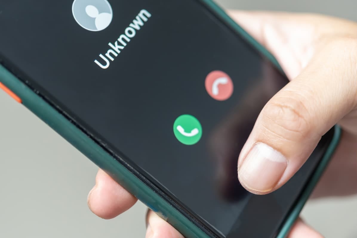 A person deciding whether to answer or decline a phone call that could be a bank scammer